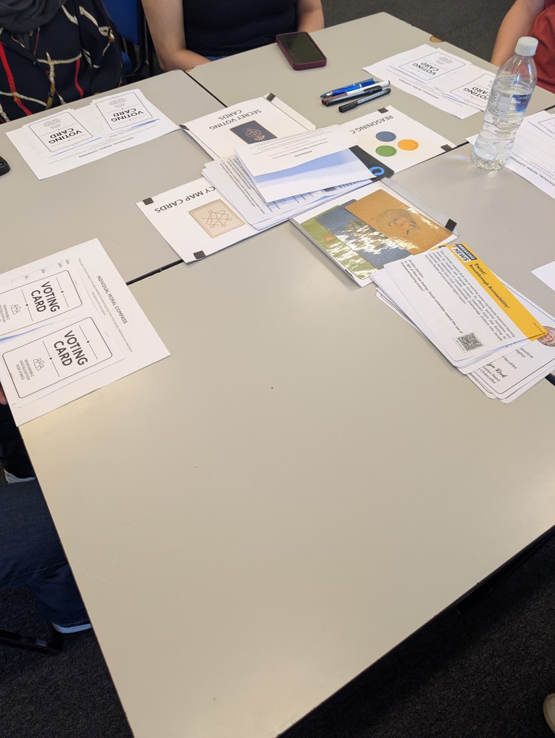 Voting cards, secret voting cards, policy map cards and a yellow twist card spread across a workshop table